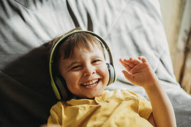 A little boy smiles emotionally and listens to music with headphones - ANAF02782