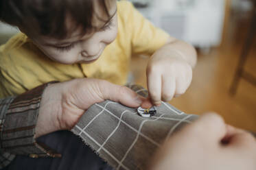 Father teaches three-year-old son to sew a button - ANAF02788