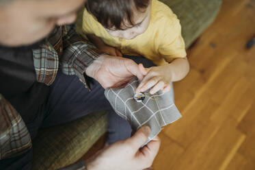 Father teaches three-year-old son to sew a button - ANAF02791