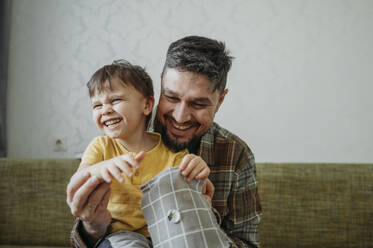 Father teaches three-year-old son to sew a button - ANAF02793