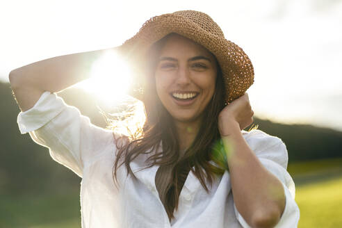 Glückliche junge Frau mit Hut an einem sonnigen Tag - JSRF02961