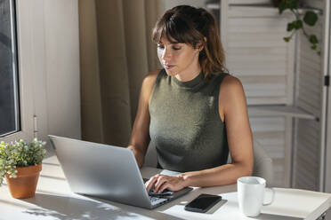 Businesswoman using laptop in office - JSRF02977