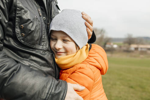 Close-up of dad's hands hugging his son outdoors - ELMF00153