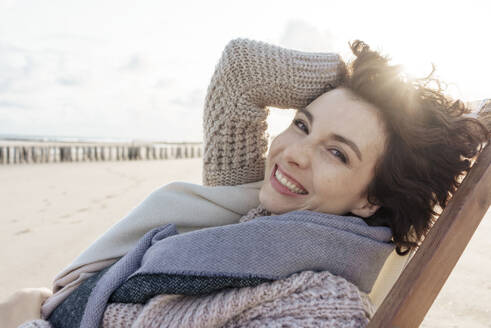 Glückliche Frau entspannt sich auf einem Liegestuhl am Strand - KNSF10188