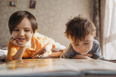 Children are reading a book at home - ANAF02804