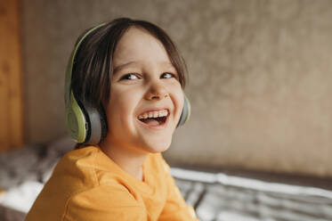 A smiling boy listens to music with headphones - ANAF02816