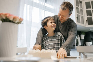 Dad and son cutting cake in the kitchen at home - ELMF00156