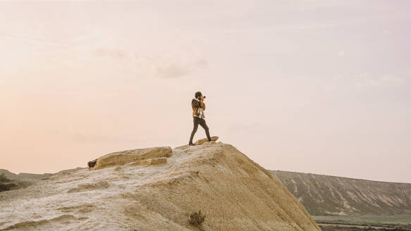 Ein einsamer Wanderer steht oben auf einer Klippe in Bardenas Reales, Navarra, Spanien, und fängt die ruhige Schönheit des Sonnenuntergangs ein. - ADSF54037