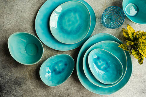 Draufsicht auf einen stilvoll gedeckten Tisch mit leuchtend türkisfarbenen Keramiktellern, Schüsseln und Gläsern - ideal für moderne Essenspräsentationen. - ADSF54059