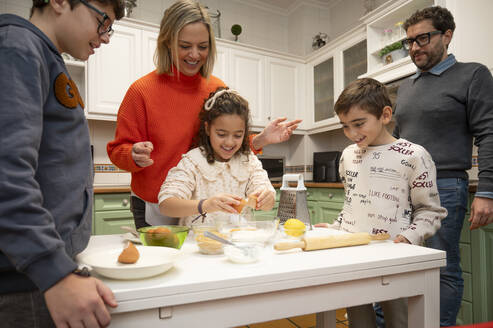 Die Familie genießt es, beim Backen zusammenzukommen, wobei die Kinder aktiv mitmachen und die Eltern in einer gemütlichen Küche die Aufsicht führen. - ADSF54096