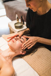 A therapist giving a relaxing facial massage to a female client in a serene spa setting - ADSF54188