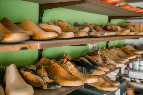 Wooden shoe lasts in various sizes and shapes line the shelves of a traditional shoemaker's workshop in Austria, representing the timeless craft of custom shoemaking. - ADSF54207