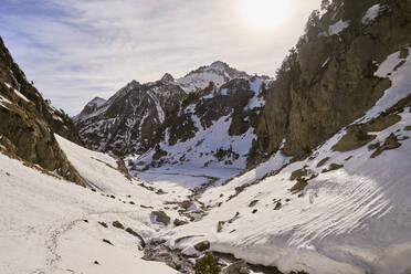 Ein ruhiger Winterblick auf das verschneite Remuñe-Tal in den Pyrenäen in der Nähe von Benasque, mit schroffen Gipfeln und einem klaren Himmel darüber. - ADSF54252