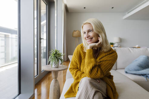 UAE, a smiling woman on a sofa by the window - TYF00820