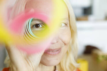 UAE, a woman looking through a rainbow spring toy - TYF00833