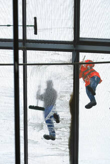 Directly below view of two window washers on glass ceiling - JTF02406