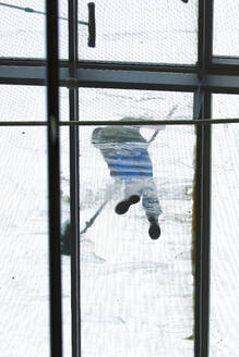 Directly below view of window washer on glass ceiling - JTF02407