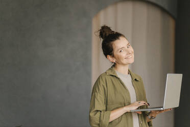 Gdansk, Poland, portrait of a girl on a gray background in a green shirt with laptop - VIVF01317