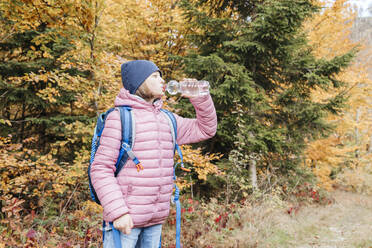 a girl drinks water from a bottle in the autumn forest during a short hike - ELMF00161