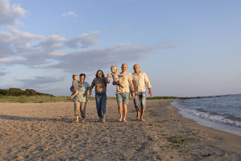 Change of generations. Seed in the second generation. Adults walk along the beach in the setting sun. - OSVF00021