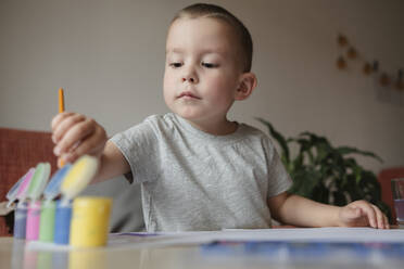 Portrait of a child of preschool age painting with paints at a table at home - KVBF00082
