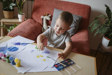 Portrait of a child of preschool age painting with paints at a table at home - KVBF00086