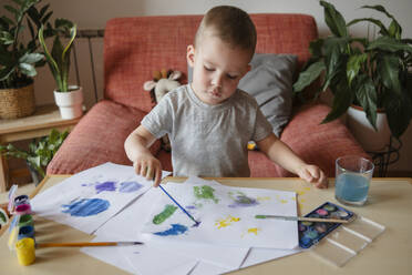 Portrait of a child of preschool age painting with paints at a table at home - KVBF00088