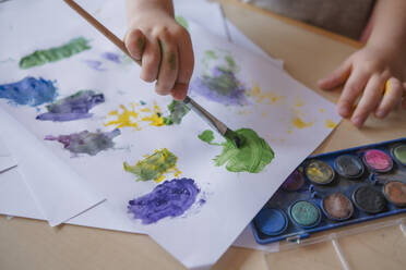 child of preschool age painting with paints at a table at home. children's hands with a brush in their hands close-up - KVBF00089