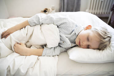 A 6 years old boy in blue pyjama is lying in the bed and sleeping - NJAF00923