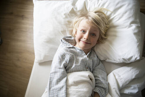 A 6 years old boy in blue pyjama is lying in the bed - NJAF00924