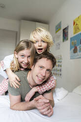 A father man with European appearance and his children blond 9 years old girl with long hair and blond 6 years old boy in pyjamas are lying in the bed - NJAF00931