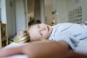 A 6 years old boy with blue eyes in blue pyjama is lying in the bed - NJAF00933