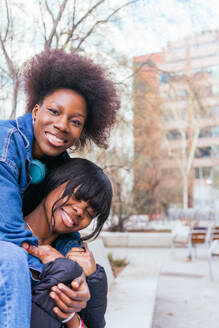 Captured in a spontaneous moment of joy, two sisters share a heartfelt embrace, their smiles radiating genuine affection and happiness - ADSF54438