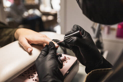 Close-up shot capturing a nail technician applying nail polish to a client's nails at a professional beauty salon - ADSF54496