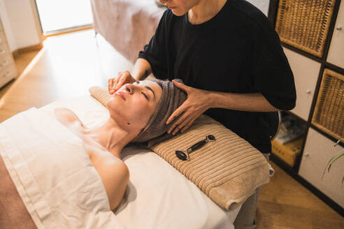 An individual enjoying a calming facial treatment involving massage and skin care at a serene spa setting - ADSF54502