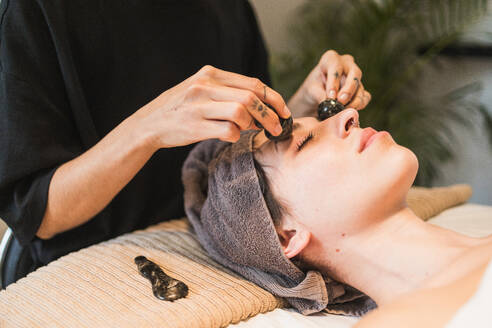 A person receives a calming gua sha facial treatment in a serene spa setting - ADSF54507