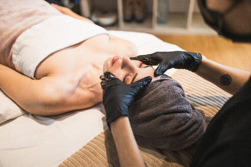 Woman receiving a relaxing facial treatment at a spa with a therapist wearing gloves - ADSF54509