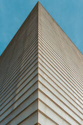 From below skyscraper's sharp corner against a clear blue sky, showcasing modern architectural design and repetitive line patterns. - ADSF54555