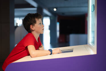 A young boy intently examines interactive displays at a science museum, showcasing a moment of educational fun and discovery. - ADSF54571