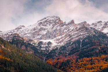Stunning autumn scenery in Ordesa's Bujaruelo Valley, Pyrenees, with snow-capped peaks contrasting with vibrant orange and yellow foliage. - ADSF54640