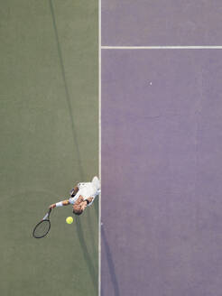 Aus der Vogelperspektive wird ein Mann beim Aufschlagen eines Tennisballs auf einem Platz aufgenommen, wobei der Sport in Aktion gezeigt wird. - ADSF54726