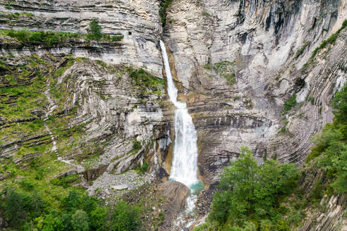 Luftaufnahme eines beeindruckenden Wasserfalls, der über die geschichteten Felsen des Valle de Ordesa im Herzen des Nationalparks von Huesca stürzt - ADSF54762
