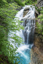 Die ruhige Schönheit eines stufenförmigen Wasserfalls mit kristallblauen Becken, eingebettet in den üppigen, grünen Wald von Valle de Ordesa, Huesca - ADSF54763