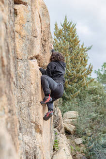 Anonymous focused climber makes their way up a steep cliff, demonstrating skill and concentration amidst a natural landscape - ADSF54779