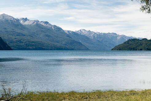 Im ruhigen Wasser eines patagonischen Sees spiegeln sich die umliegenden Bergketten und üppigen Wälder unter einem klaren blauen Himmel - ADSF54785