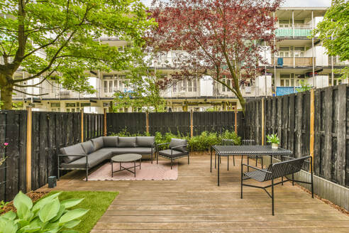 Eine Terrasse mit Sofa und Tischen in einem Innenhof - ADSF54841