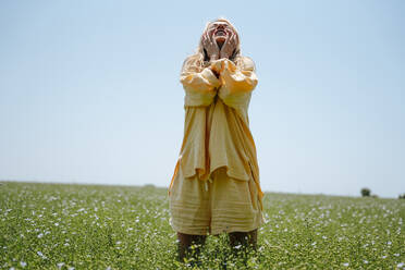 A young woman in a yellow linen suit in a blooming field - MDOF01970