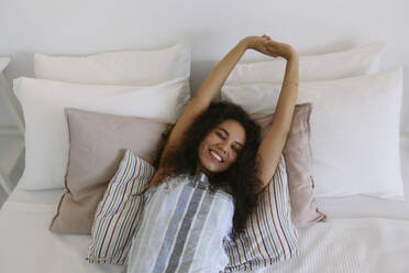 Black young woman relaxing on a bed alone. - SYEF00534