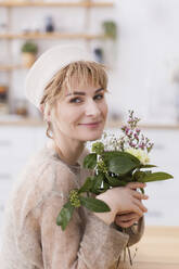 Ukraine, woman in stylish hat holding bouquet of flowers - ONAF00768