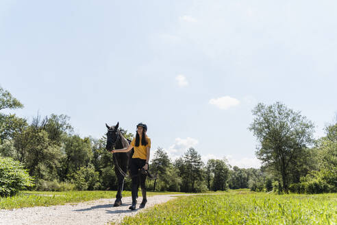 Ausbilderin mit Pferd auf dem Manegenplatz an einem sonnigen Tag - NDEF01651